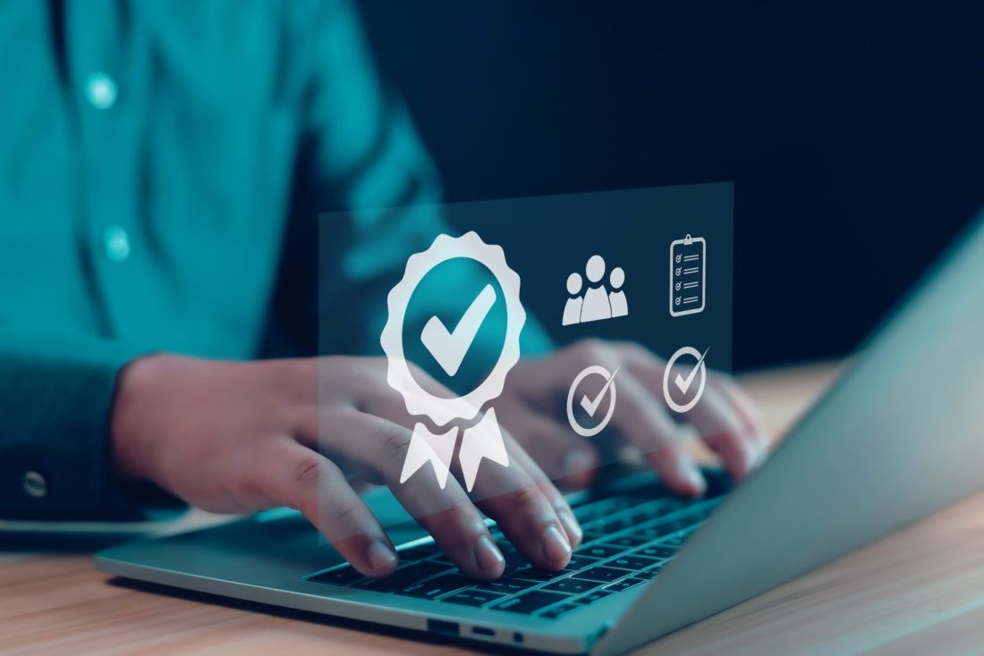 Person typing on a laptop with a tick badge overlayed